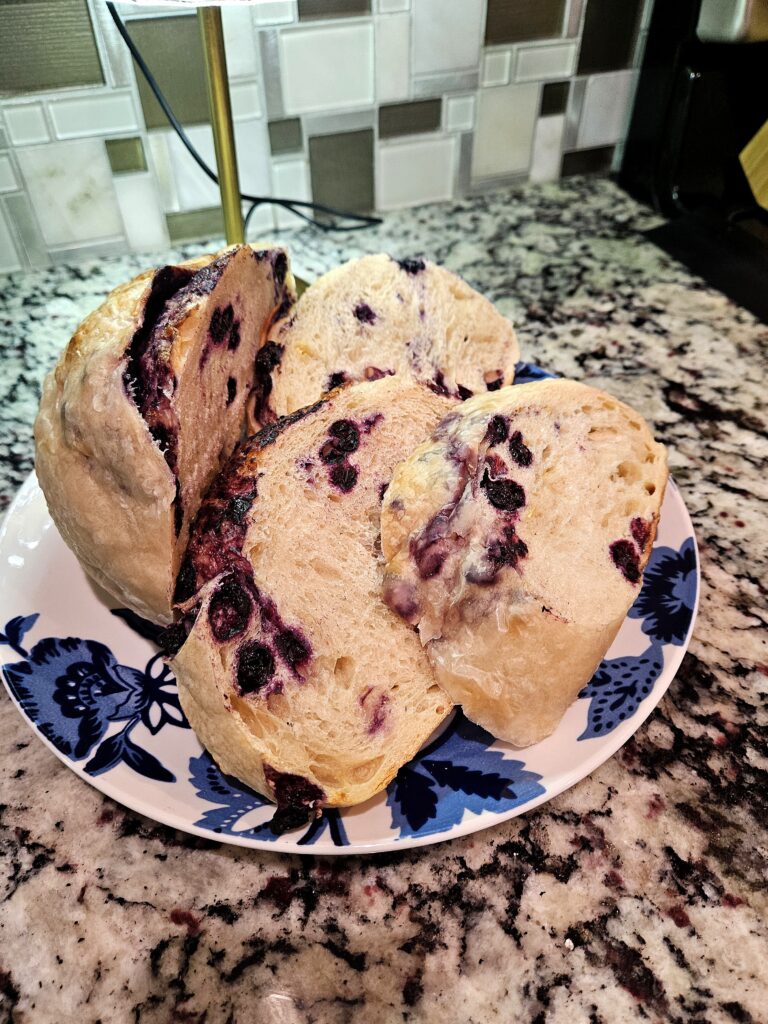 Sliced lemon blueberry sourdough bread on a plate showing a soft interior with blueberries throughout