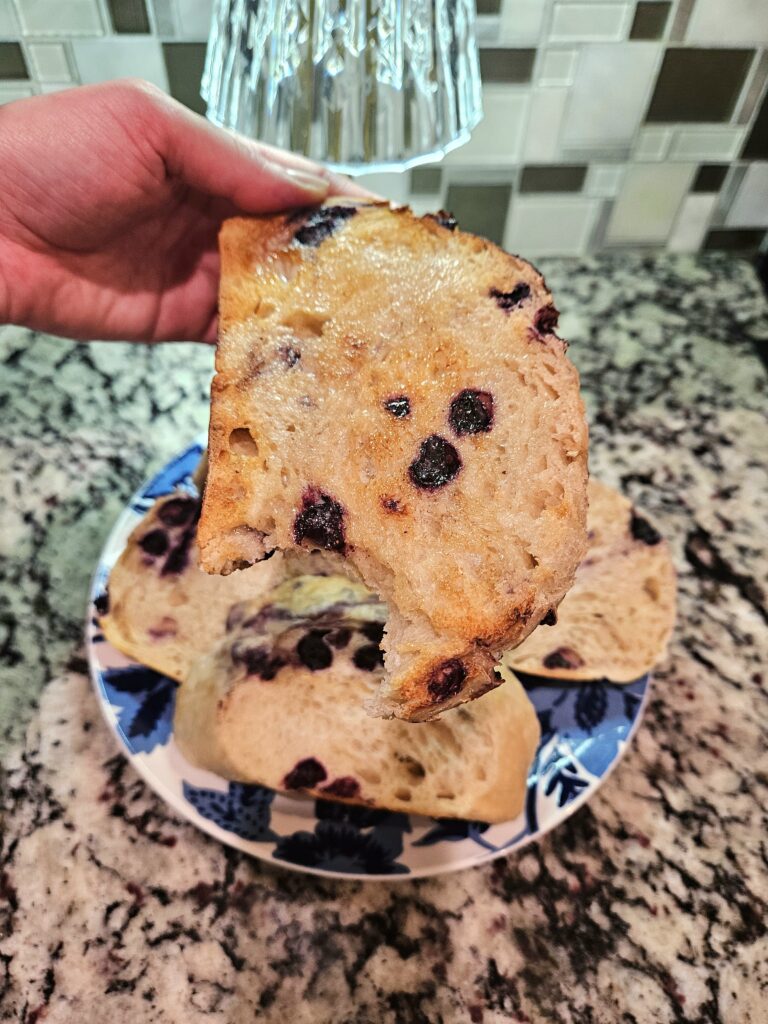 Close-up of a toasted slice of lemon blueberry sourdough with melted butter and baked-in blueberries