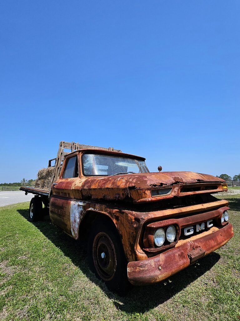 Rusted vintage GMC farm truck parked in a field at the Florida Agricultural Museum