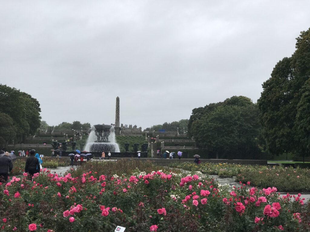 Fountain and flower gardens in Vigeland Park with the Monolith visible in the distance