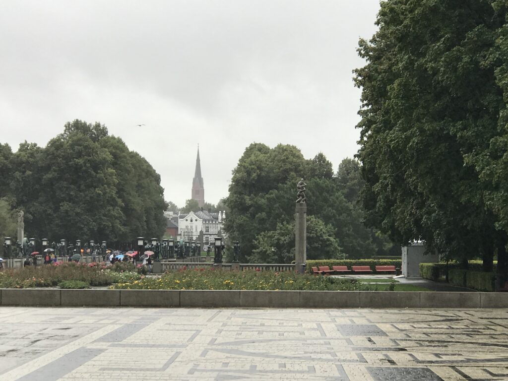 View across Vigeland Park toward Oslo skyline with church spire in the distance