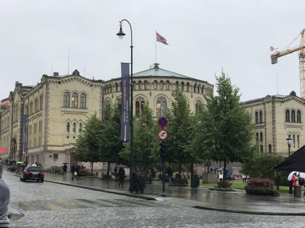 Norwegian Parliament building in Oslo with flag and wet streets after rain