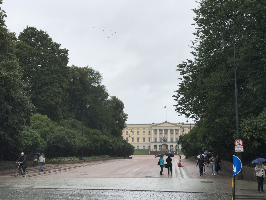 Tree-lined path leading toward the Royal Palace in Oslo on a cloudy day