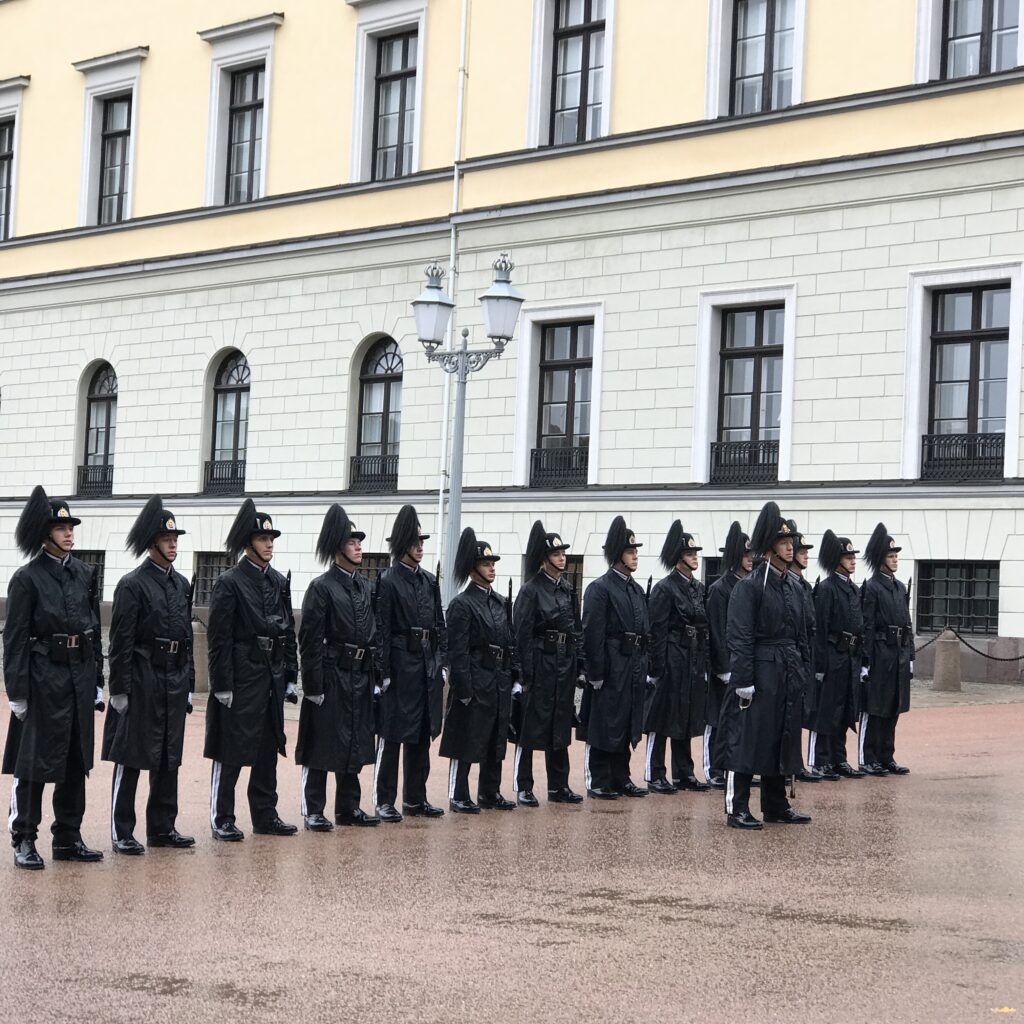 Royal guards standing in formation outside Oslo palace in the rain