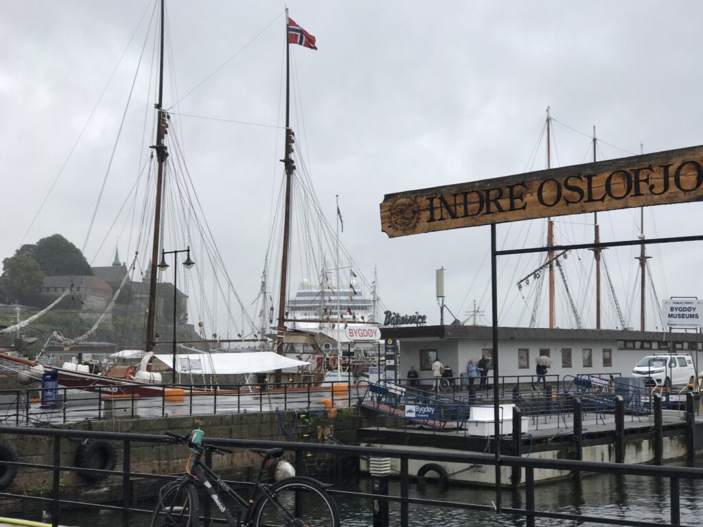 Entrance sign to Aker Brygge waterfront area with boats docked in Oslo