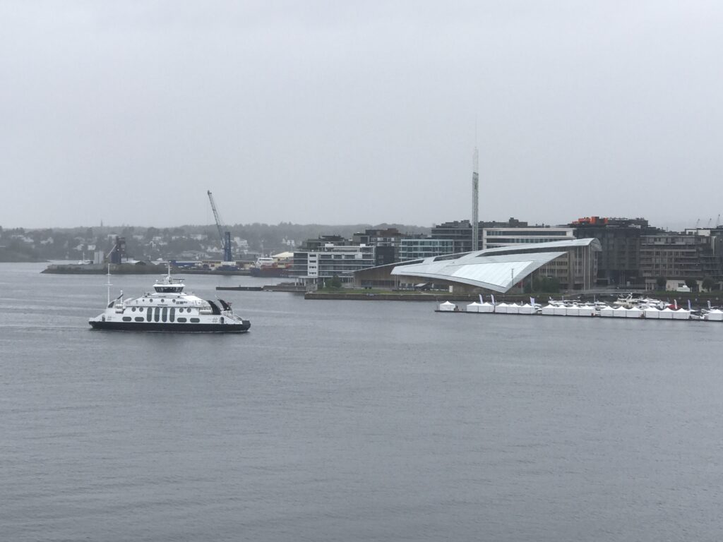 Ferry crossing Oslo harbor with modern waterfront buildings in the distance