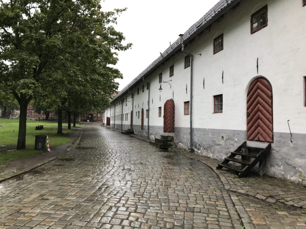 Cobblestone path and historic white buildings inside Akershus Fortress grounds