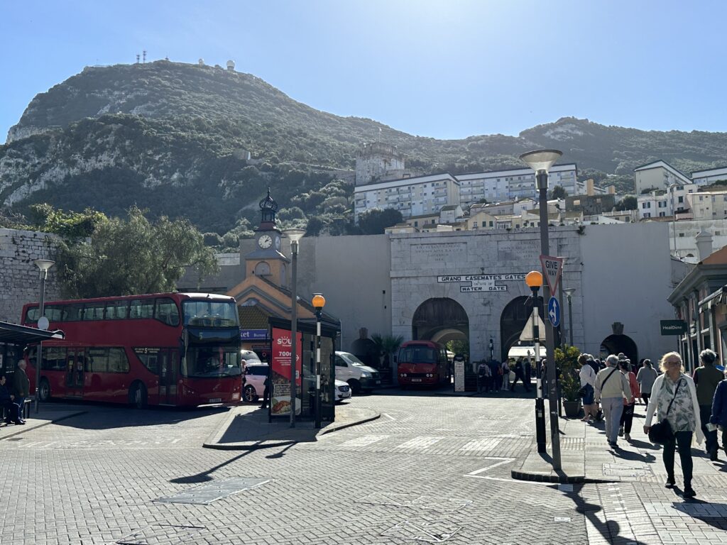 Grand Casemates Square in Gibraltar with buses, historic buildings, and the northern entrance to the city walls.