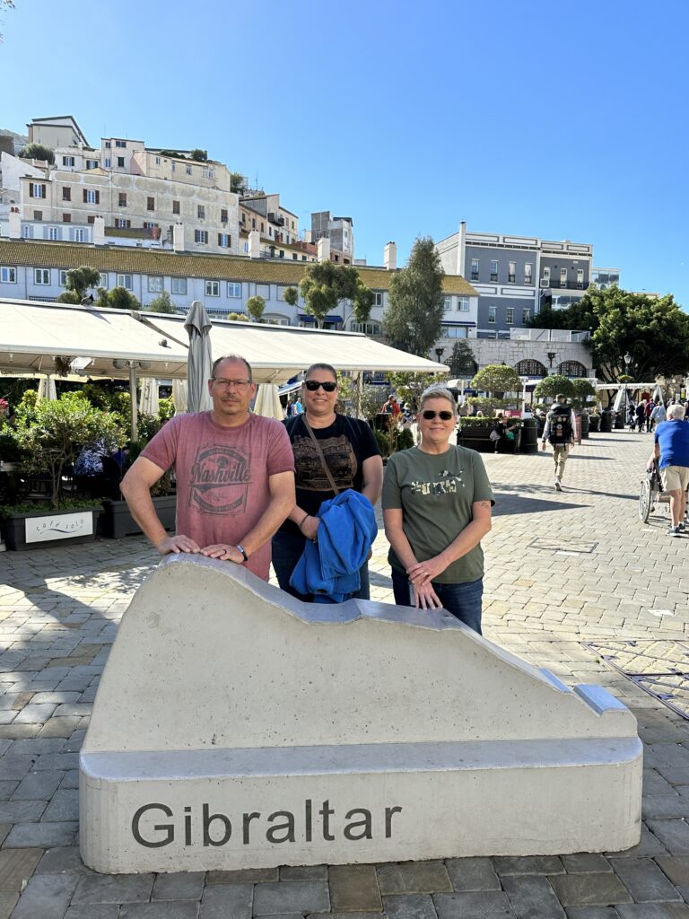 Visitors Jeff (left), Lori (middle), and Pam (right) posing in Casemates Square with restaurants and buildings lining the plaza in Gibraltar.