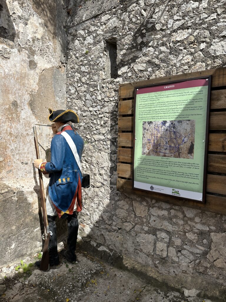 Person in historical military uniform standing beside an informational display inside the Great Siege Tunnels.