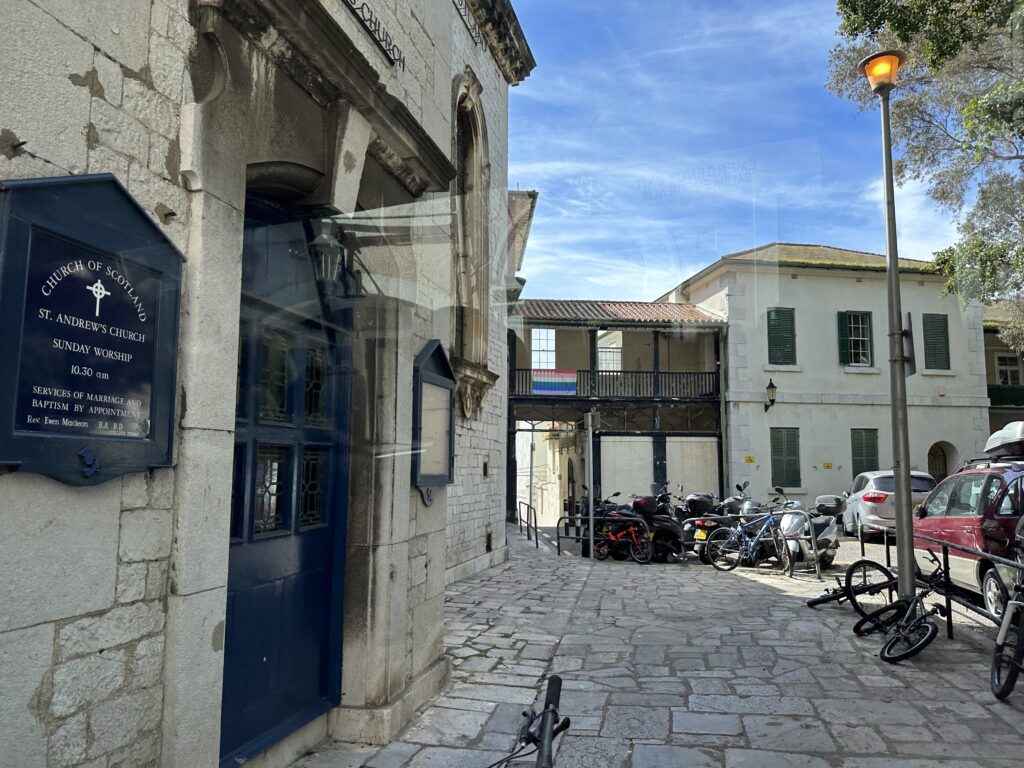 Narrow cobblestone alley in Gibraltar with stone buildings and parked scooters.