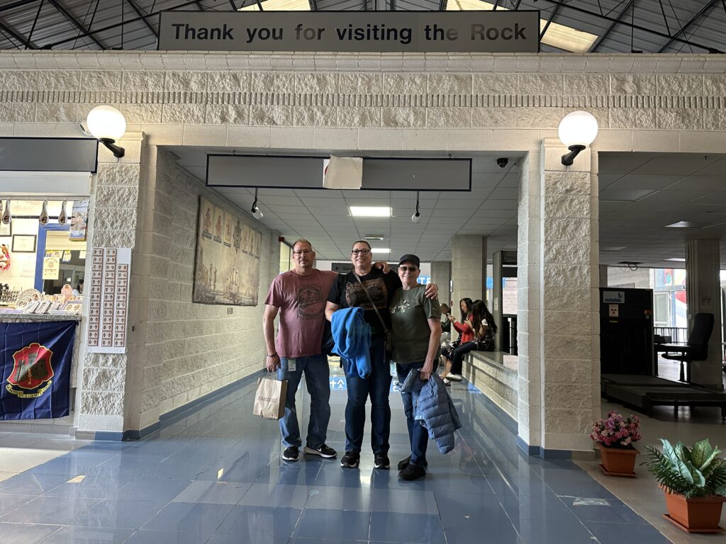 Visitors Jeff (left), Lori (middle), and Pam (right) standing under a “Thank you for visiting the Rock” sign inside a passageway in Gibraltar.