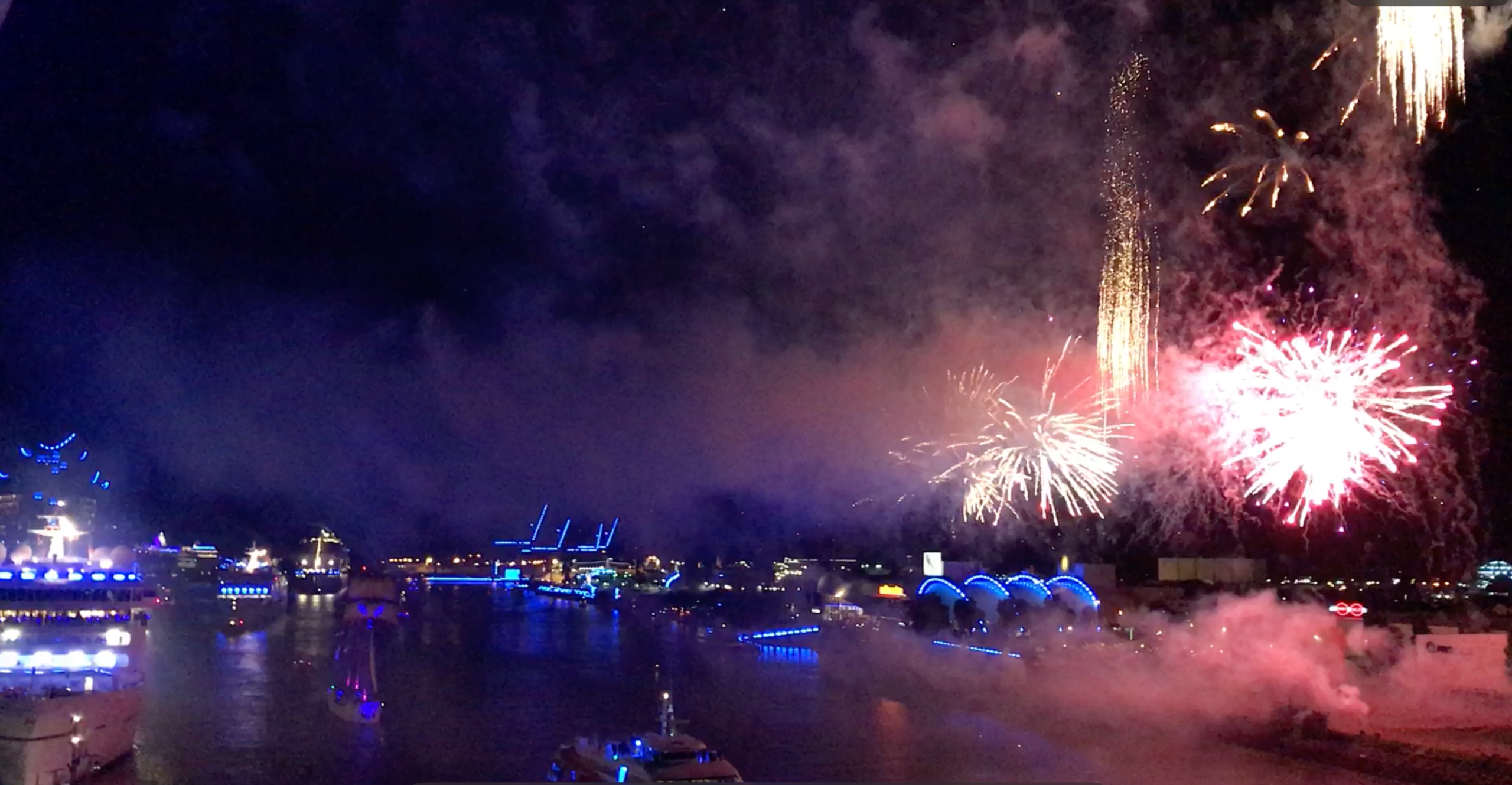 Colorful fireworks lighting up Hamburg’s harbor during Blue Port, with illuminated ships and buildings glowing blue along the water
