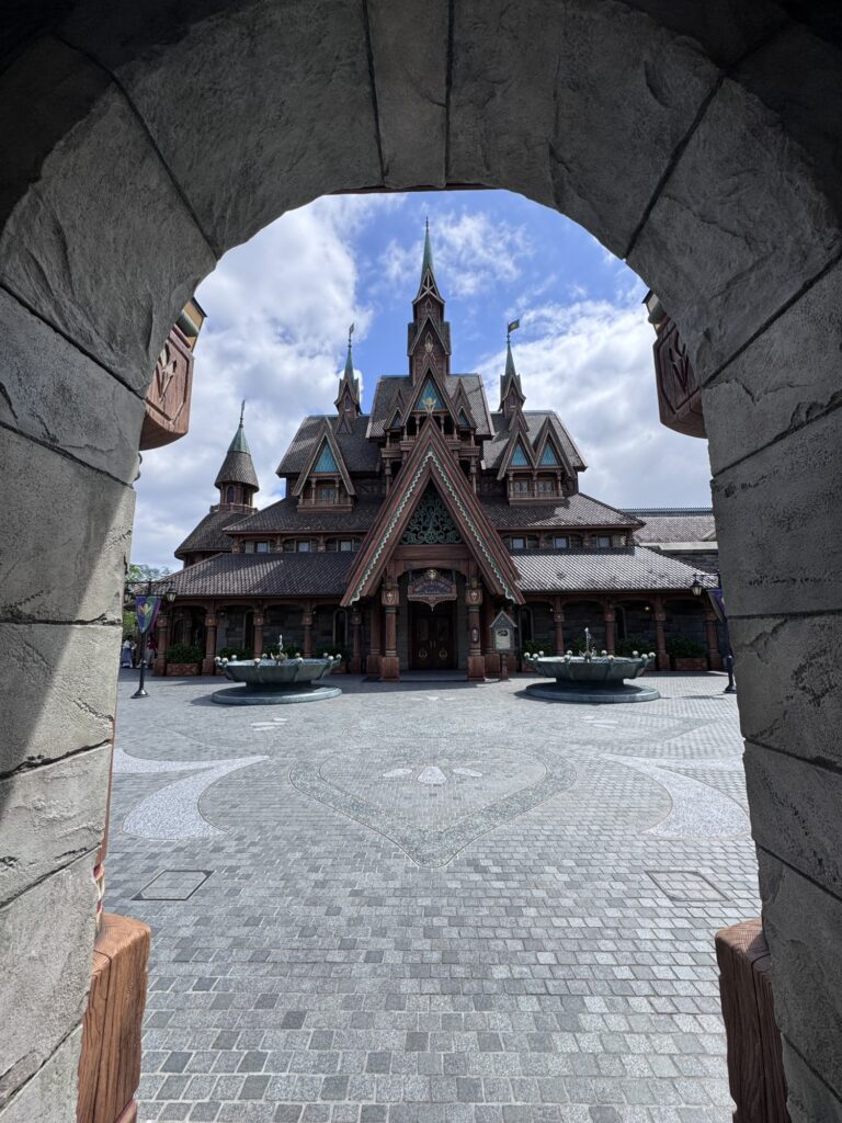View through stone arch framing Fantasy Springs building at Tokyo DisneySea with detailed woodwork