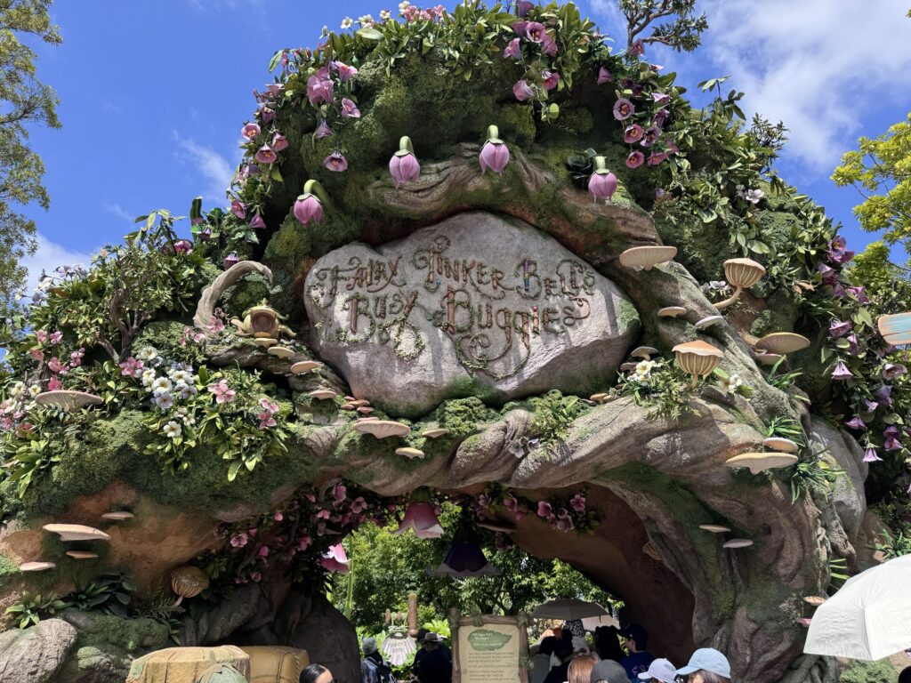 Jungle-themed entrance arch at Tokyo DisneySea’s Tinker Bell ride covered in flowers and greenery