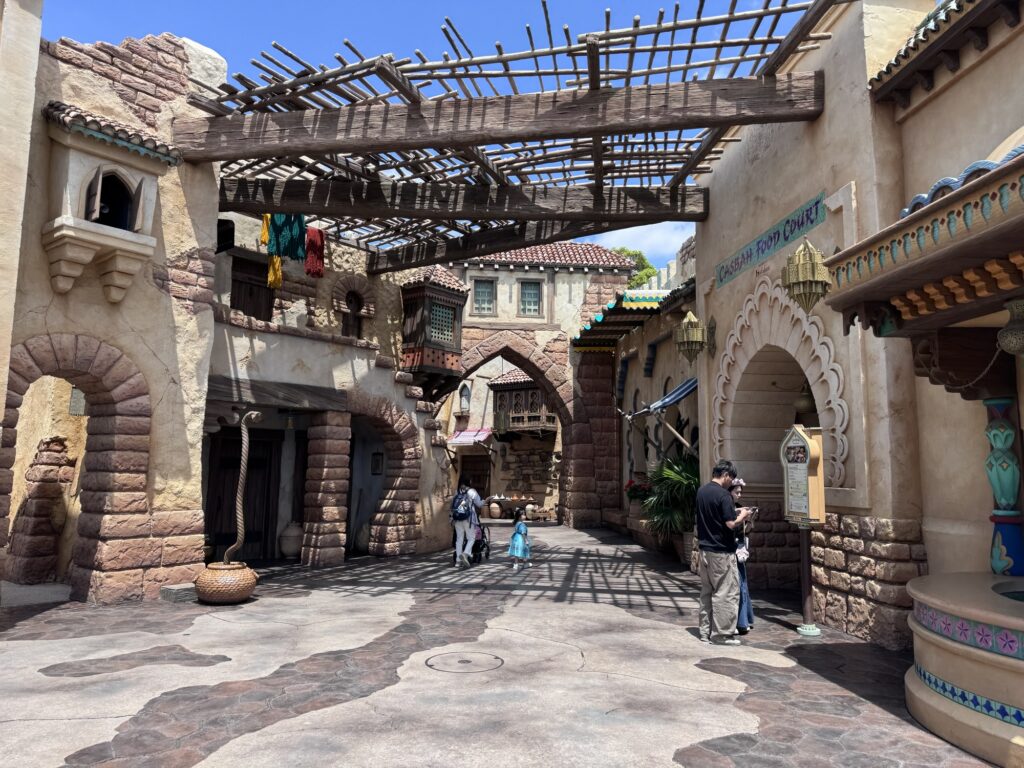 Walkway in Tokyo DisneySea’s Arabian Coast with shaded arches, textured walls, and hanging decorations