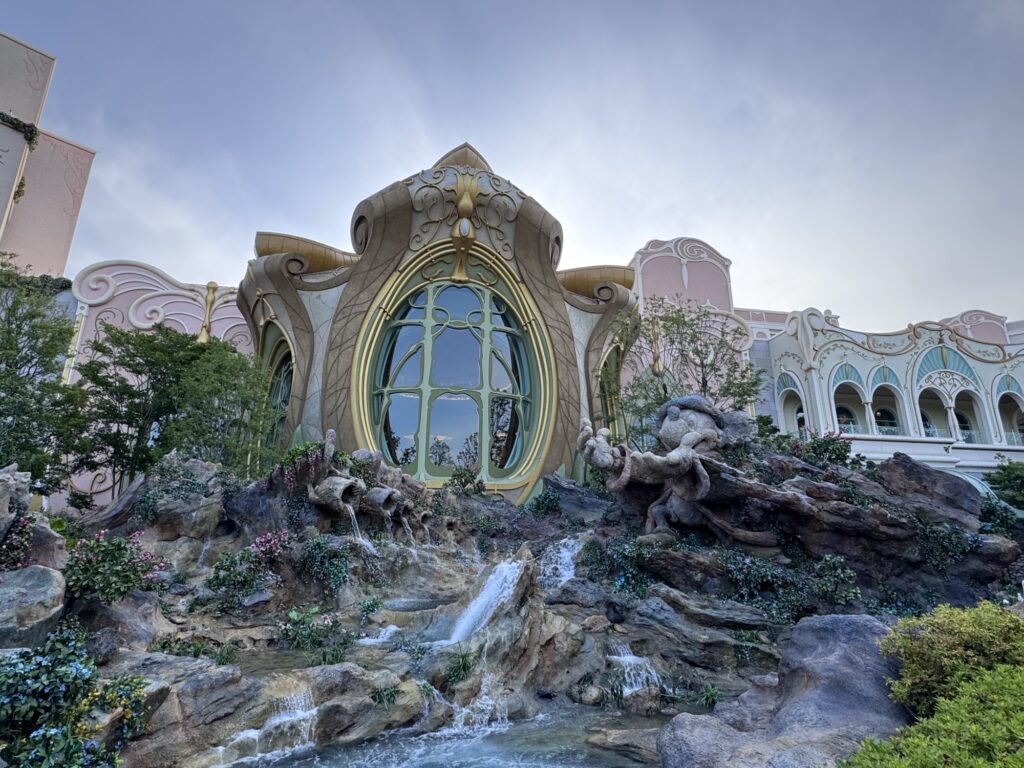 Decorative building facade at Tokyo DisneySea's Fantasy Springs Resort with large arched window, sculpted details, and cascading water feature