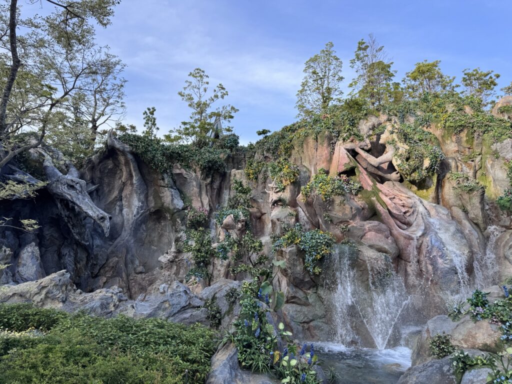 Carved figure embedded in rocky cliffside at Tokyo DisneySea with vines and weathered stone details