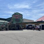 Jungle Jim's amusement park entrance with colorful signage, giraffe decoration, and visitors gathered outside on a sunny day