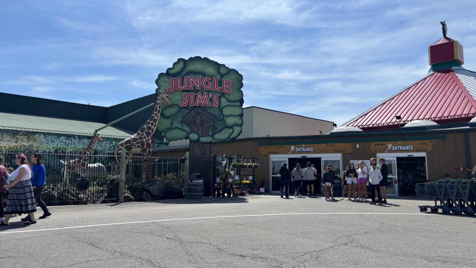 Jungle Jim's amusement park entrance with colorful signage, giraffe decoration, and visitors gathered outside on a sunny day