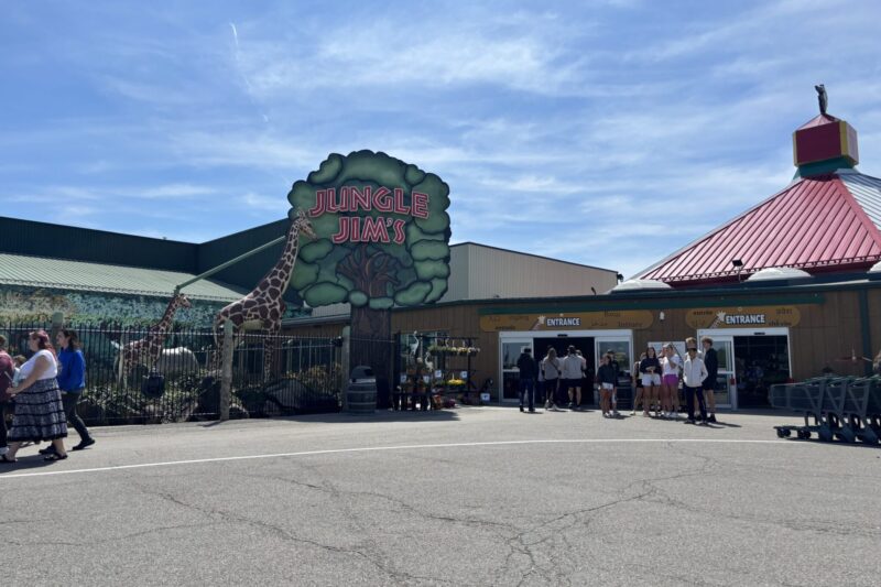 Jungle Jim's amusement park entrance with colorful signage, giraffe decoration, and visitors gathered outside on a sunny day