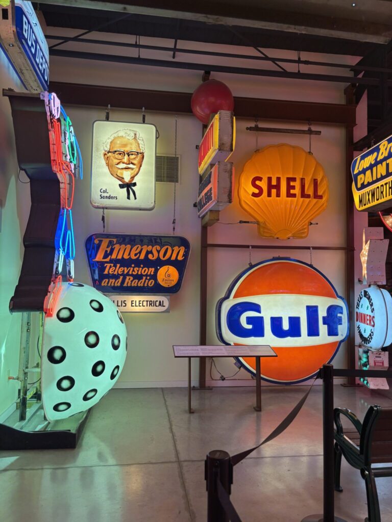 Retro neon signs for KFC, Shell gas, Gulf oil and more hanging on the wall.