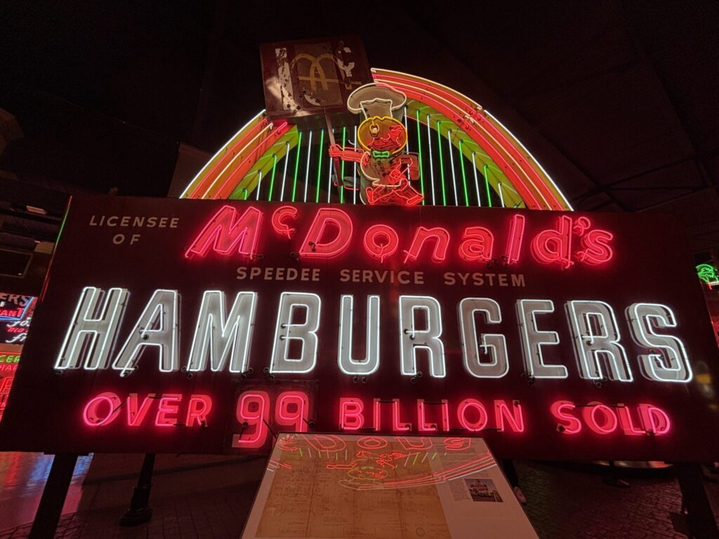 Vintage McDonald's neon sign at night displaying "Hamburgers" and "Over 99 Billion Sold" with red and green glowing tubes