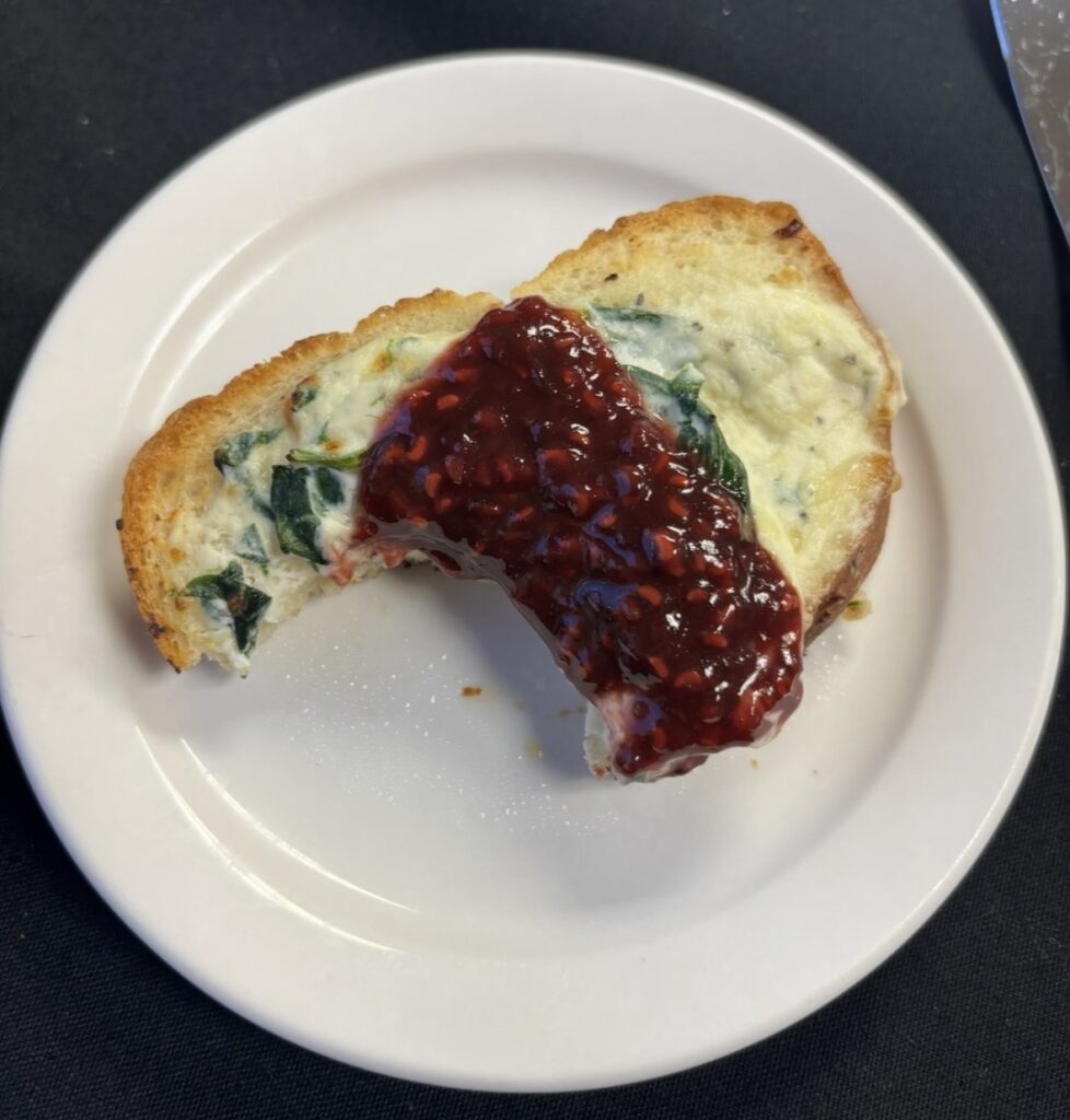 Toast topped with ricotta cheese and spinach and raspberry puree.