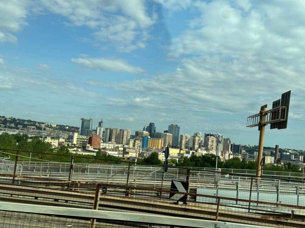 Naples skyline viewed from the highway with metal guardrails and light pole in foreground