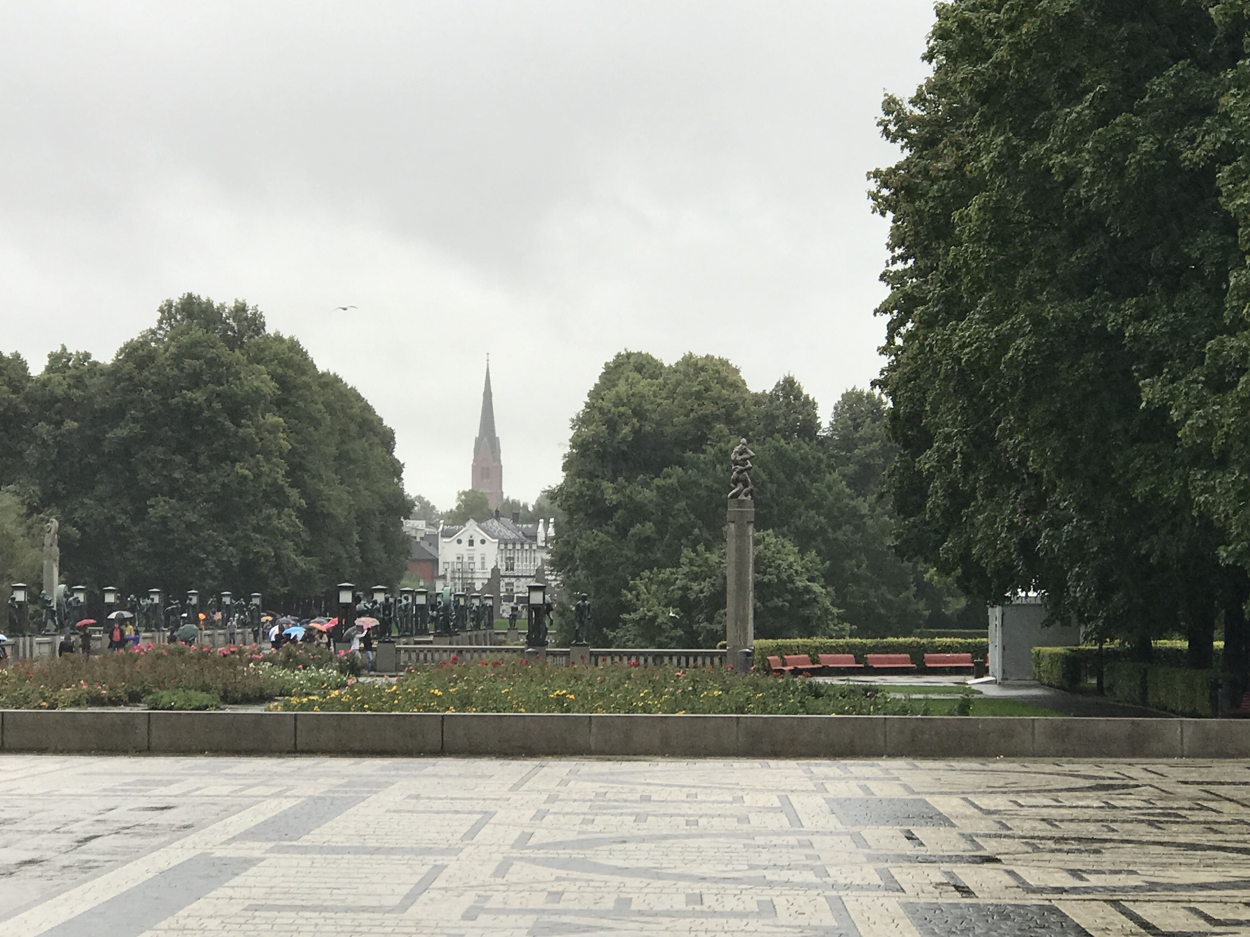 Vigeland Park Oslo Norway view toward city skyline with church spire, gardens, and rainy weather