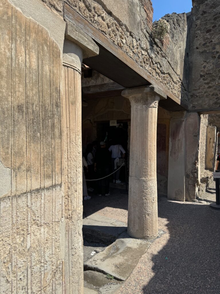 Ancient Roman stone doorway with fluted columns and weathered walls in Pompeii archaeological site