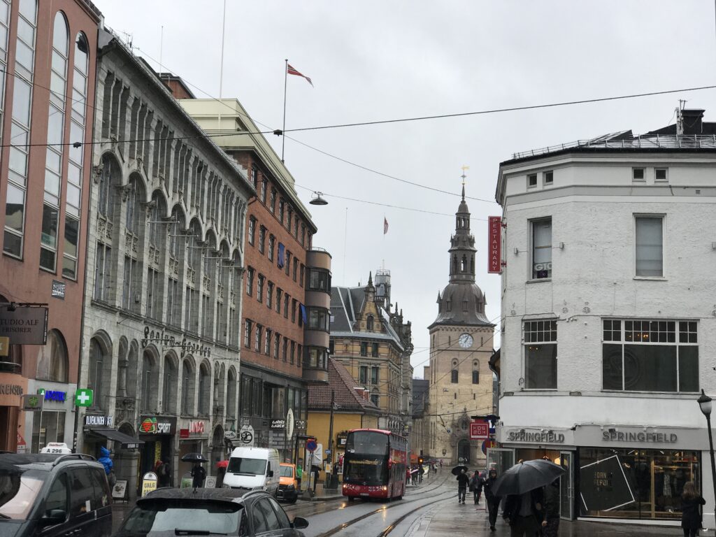 Street view in Oslo city center with historic buildings and church tower in the distance