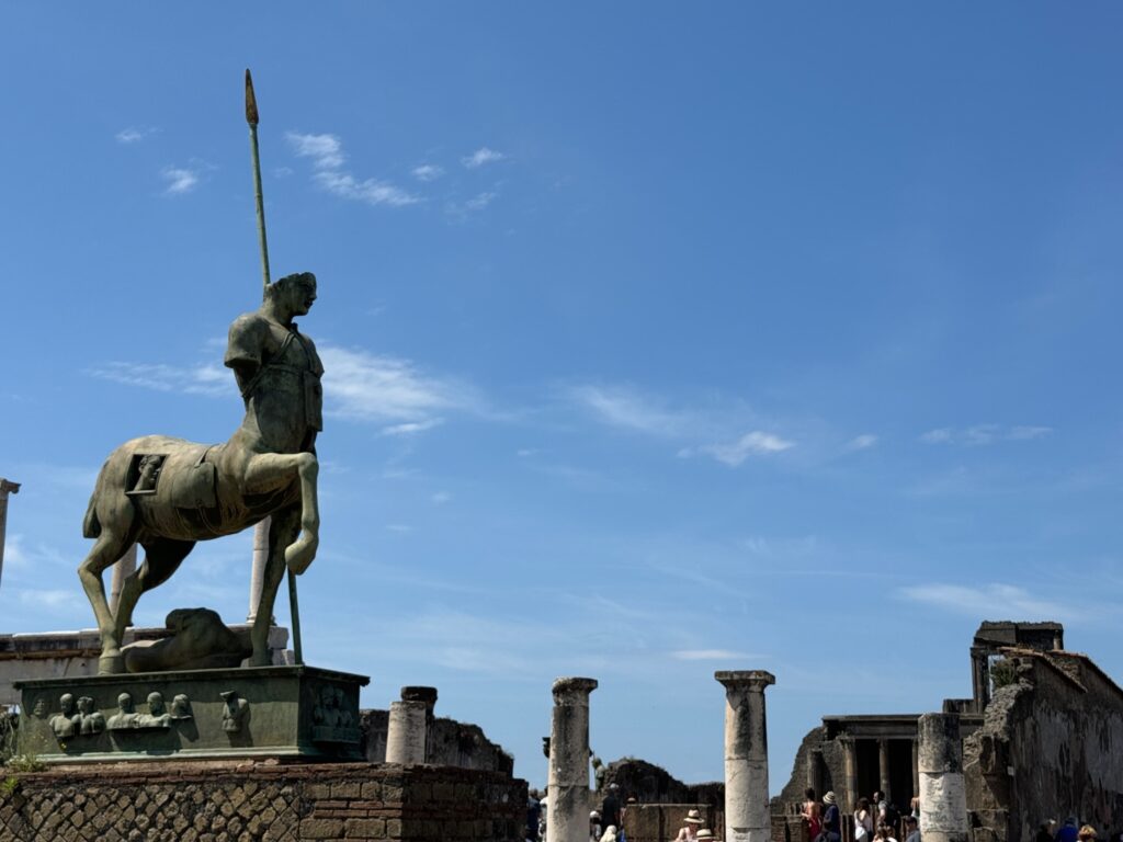 Bronze equestrian statue of a warrior with spear overlooking ancient Roman ruins with standing columns