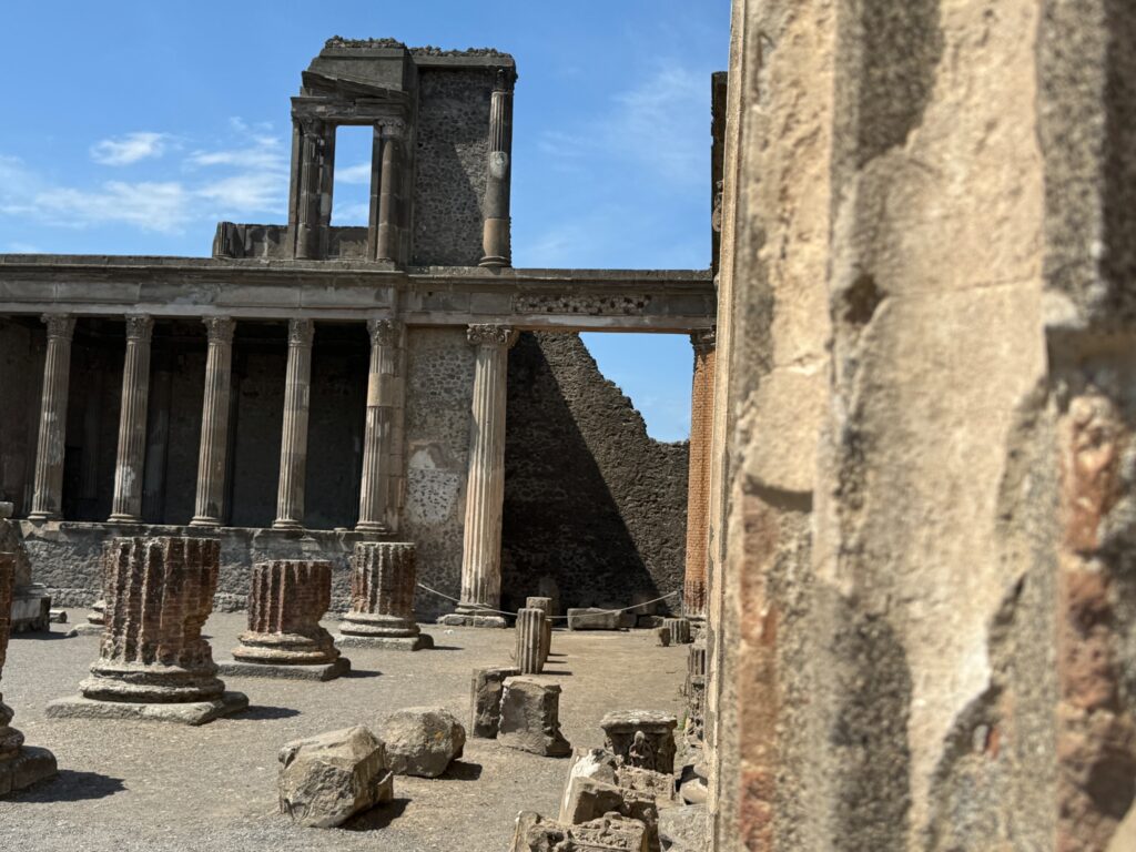 Ruins of an ancient Roman building with standing columns and stone structures against a clear blue sky