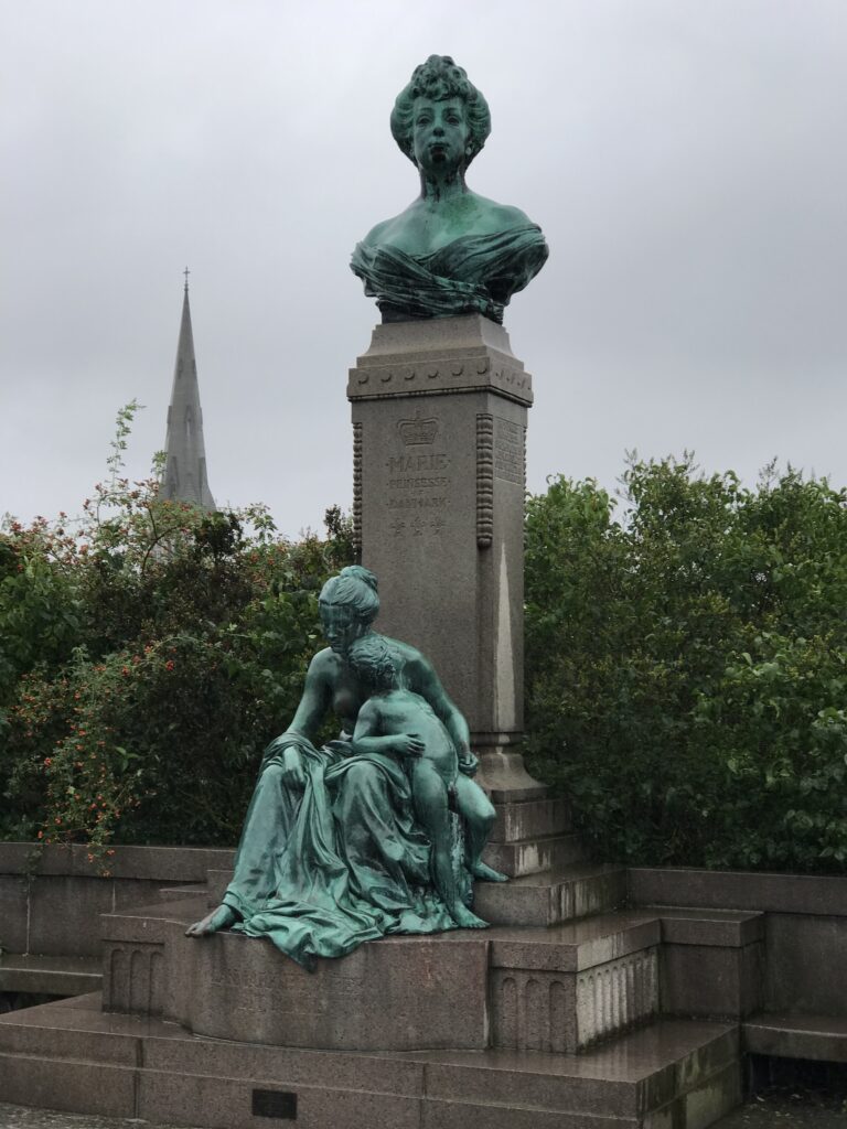 Monument and sculpture near waterfront with church spire in the background