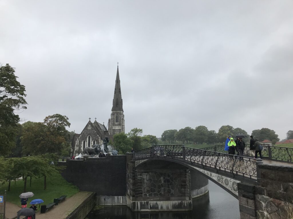Bridge over canal near Church of Our Saviour with pedestrians in light rain