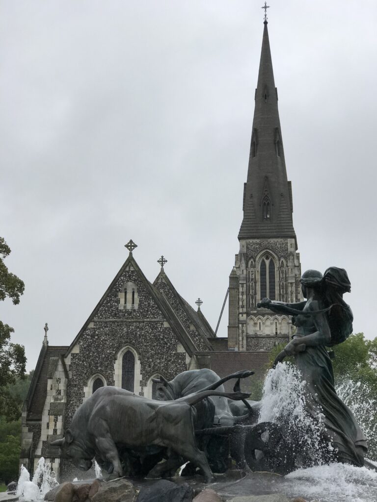 Fountain statue with Church of Our Saviour in the background on a cloudy day in Copenhagen