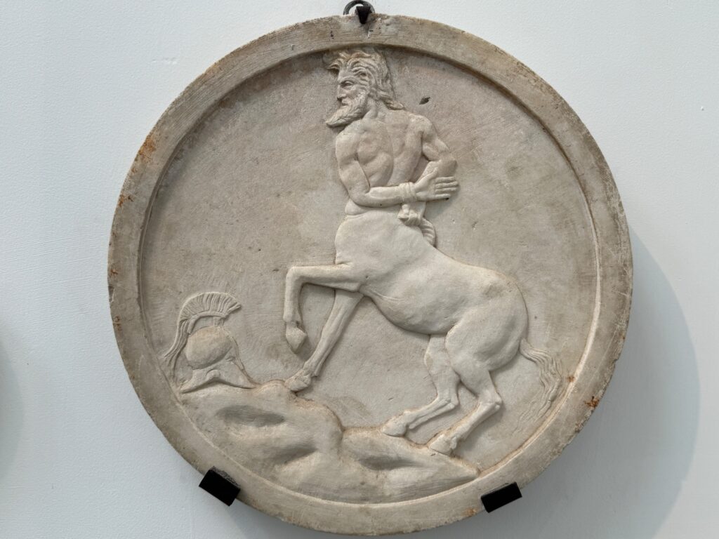 Stone relief medallion depicting a man riding a rearing horse over a fallen figure