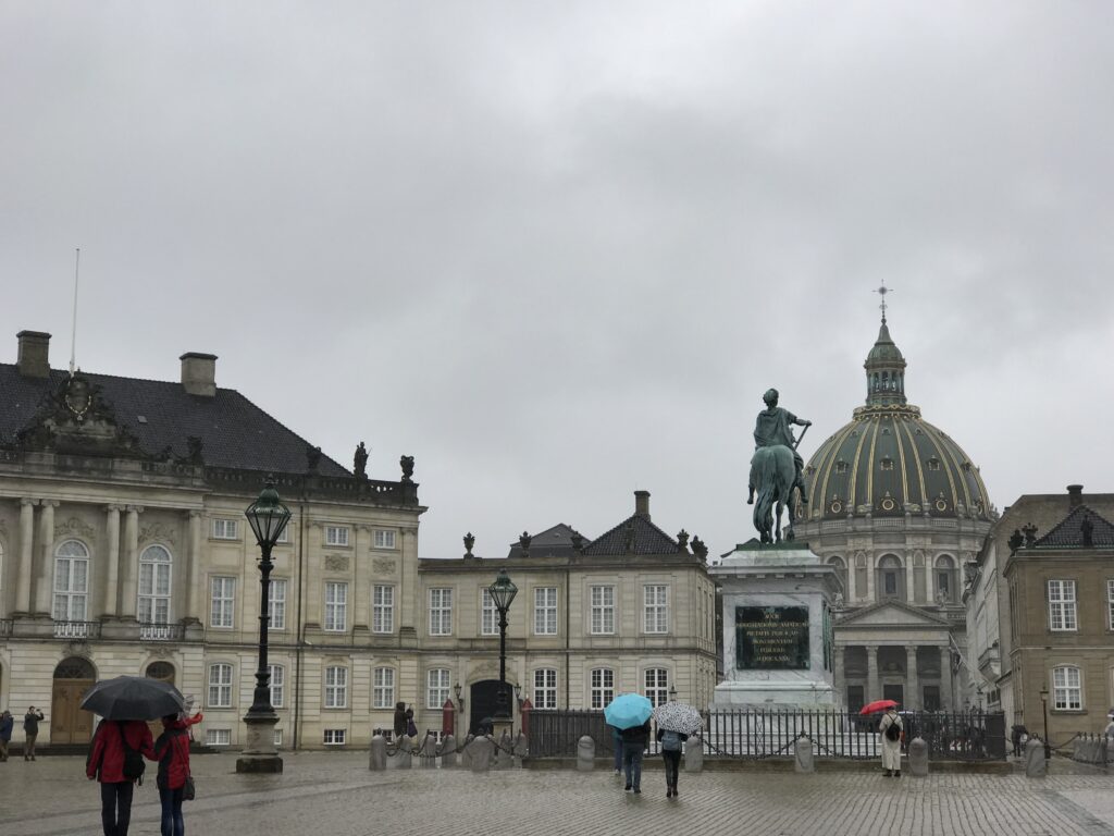 Rainy view of Amalienborg Palace square with statue and Frederik’s Church dome in Copenhagen