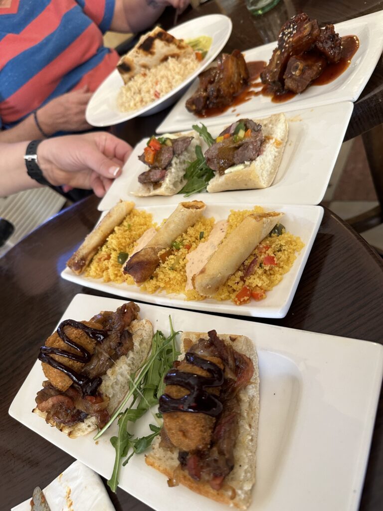 A spread of gourmet sandwiches and meat dishes served on white plates at a restaurant table during a meal