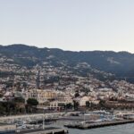 The coastline of Funchal, Maedeira, showing houses and buildings scattered across mountains.