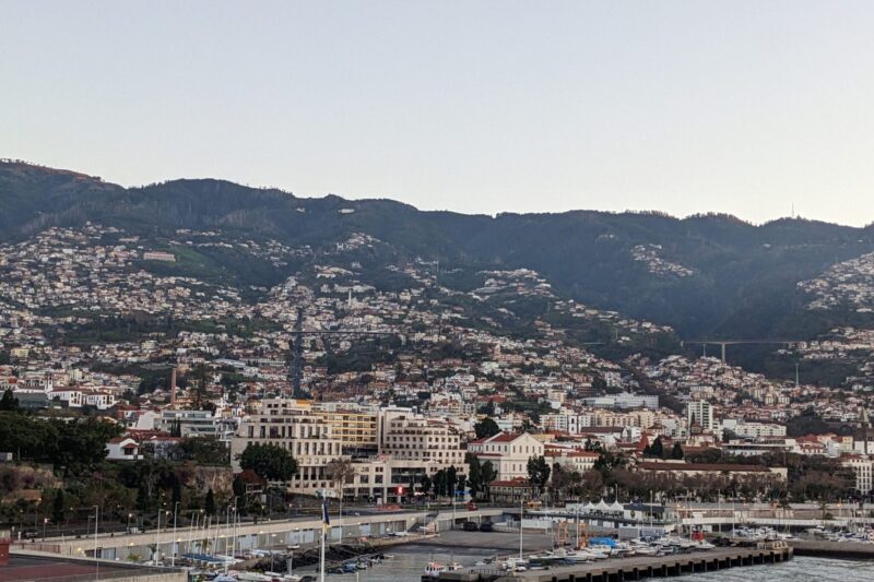 The coastline of Funchal, Maedeira, showing houses and buildings scattered across mountains.