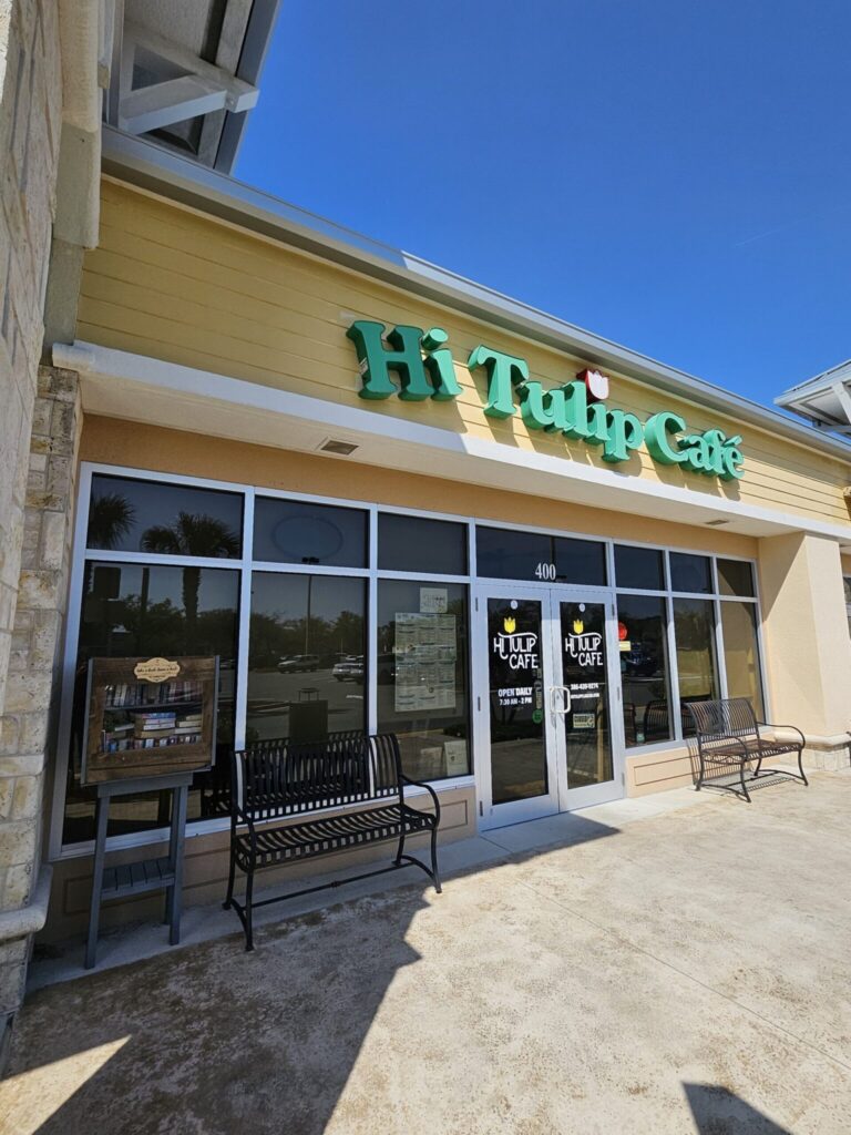 Hip Hop Café storefront with yellow siding, green signage, and large windows at address 400 on a sunny day