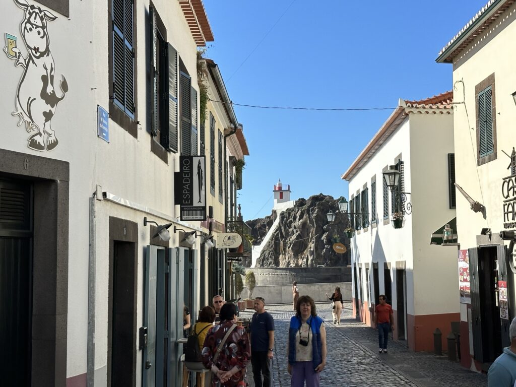 Street in Câmara de Lobos Madeira with colorful buildings and a church on the cliff in the distance