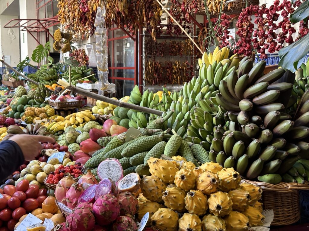 Colorful display of tropical fruits including bananas and dragon fruit at Funchal Madeira market