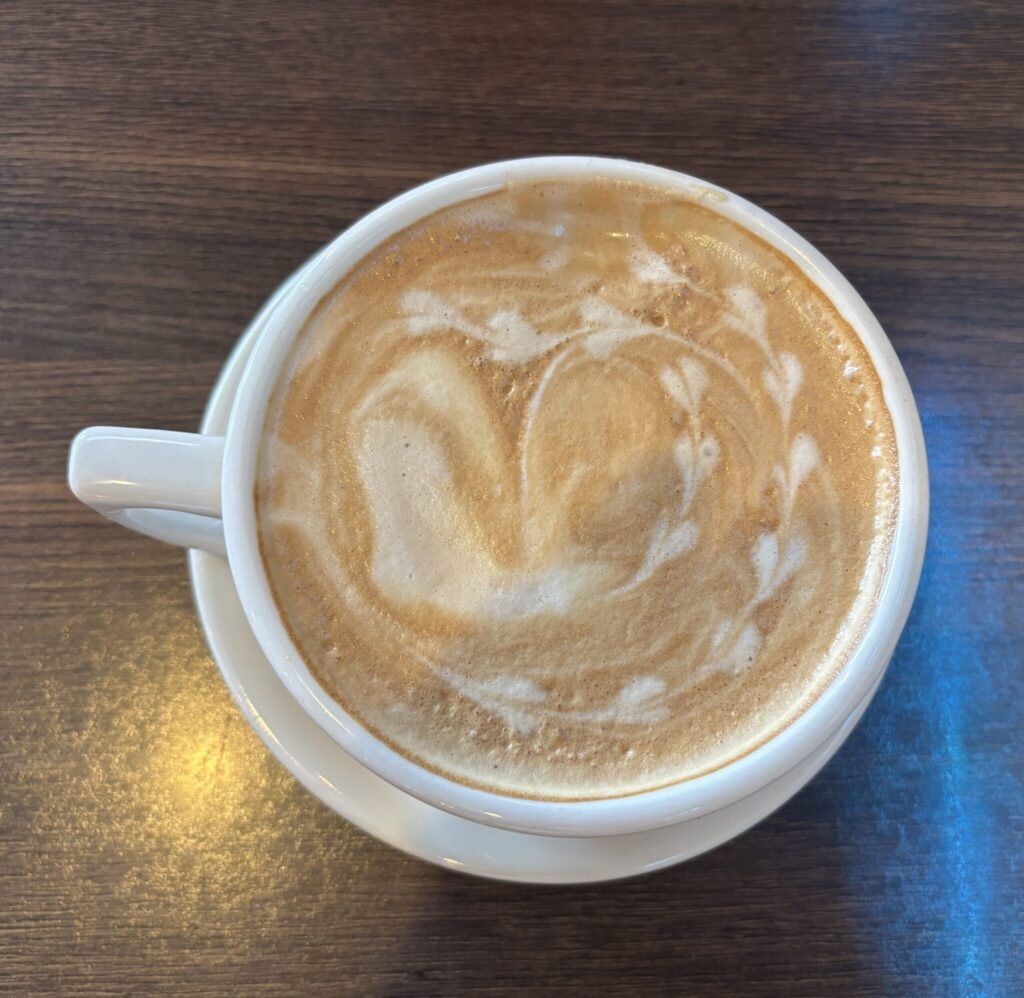 White ceramic mug of latte with latte art on a wooden surface