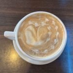 White ceramic mug of latte with latte art on a wooden surface