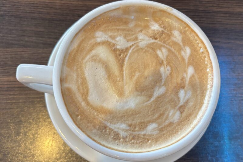 White ceramic mug of latte with latte art on a wooden surface