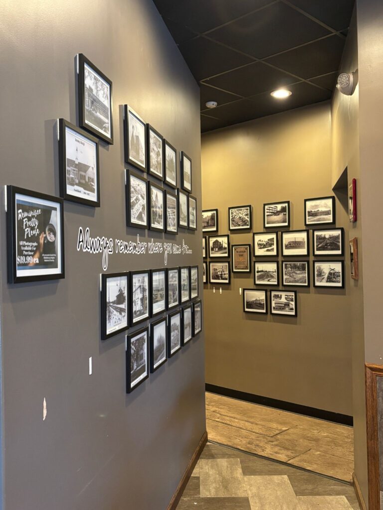 A narrow hallway displays framed historical black-and-white photographs and vintage signage on cream-colored walls with professional lighting