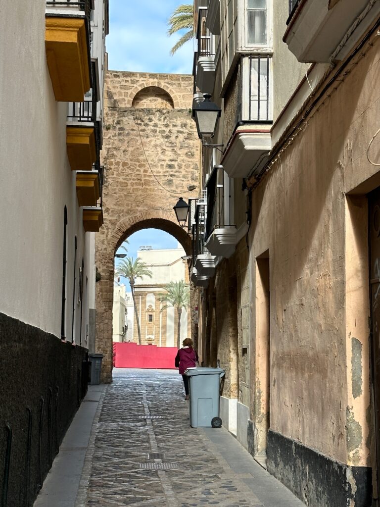 Narrow cobblestone alley in a historic Mediterranean town with arched stone gateways and traditional architecture